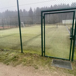Gepflegter Tennisplatz mit Maschenzaun-Eingang